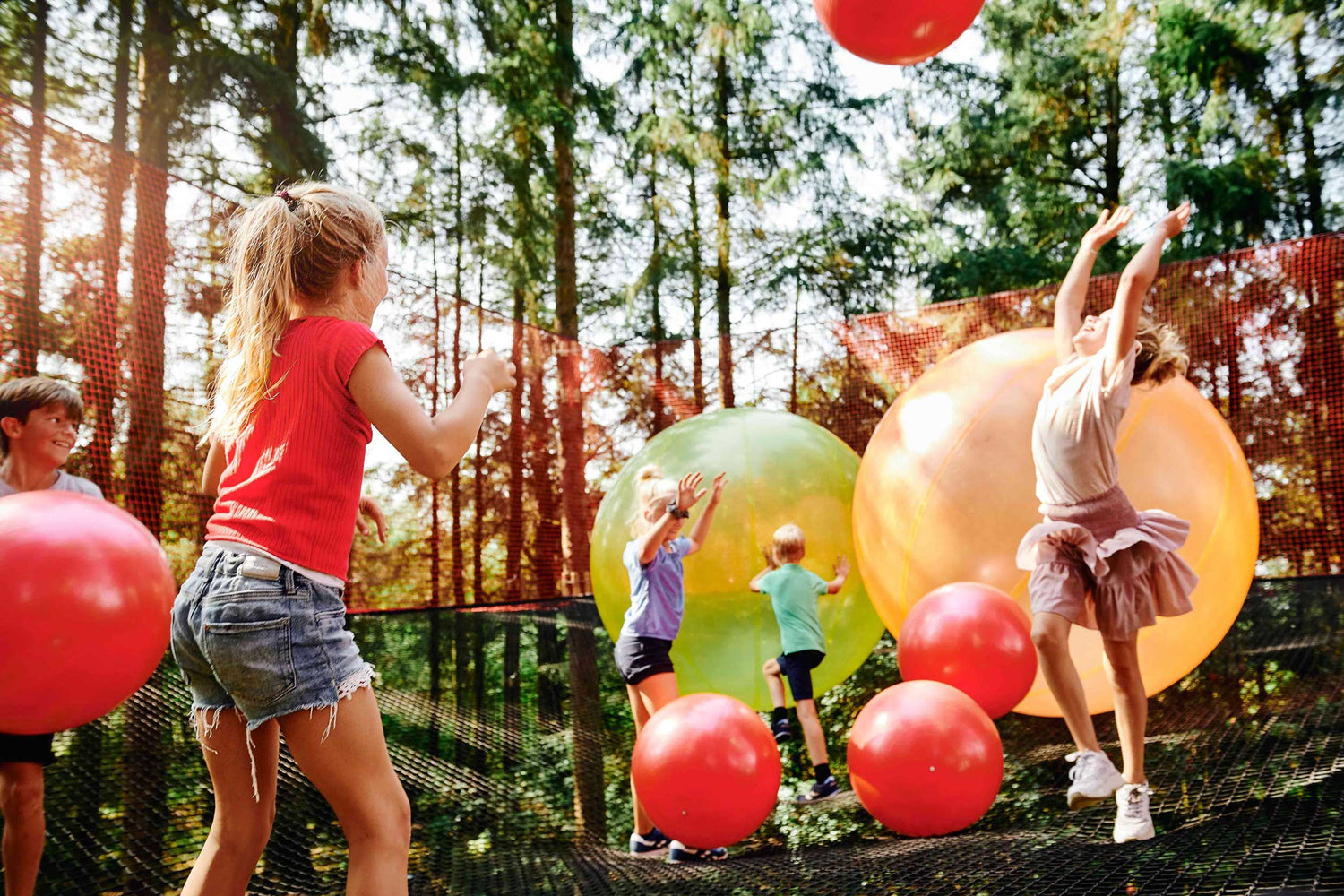 Children playing with large balls inside a big net at WOW PARK.