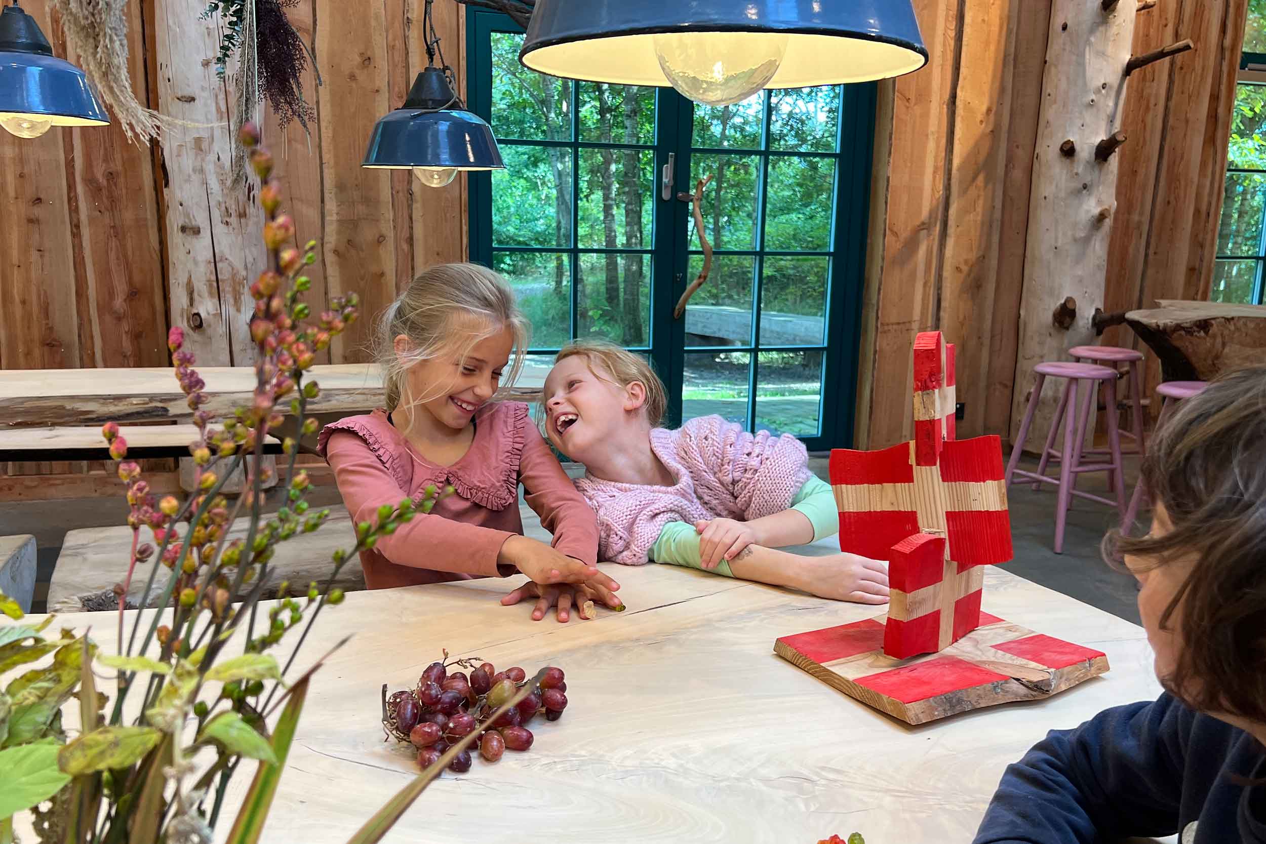 Three children are sitting in Madladen at WOW PARK Billund, celebrating a birthday party.
