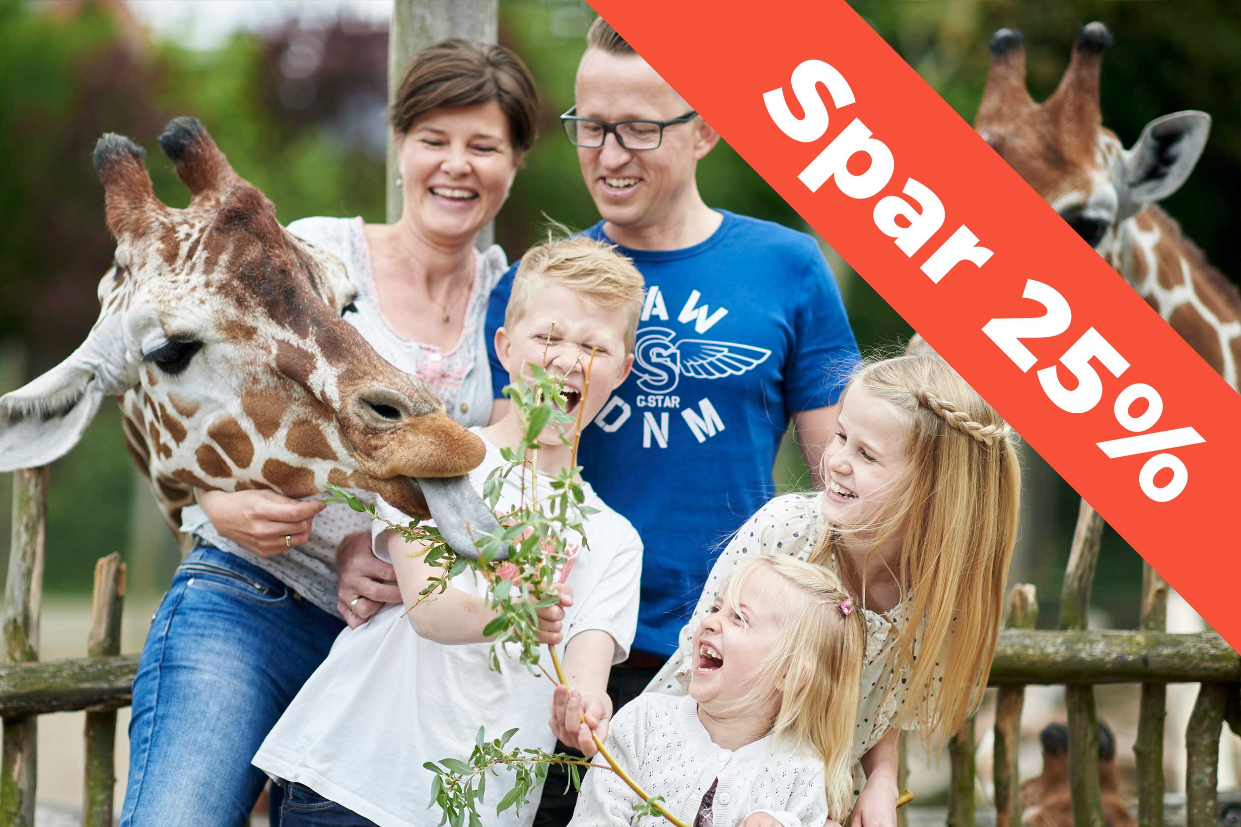 En familie står sammen med en giraf i Odense Zoo.