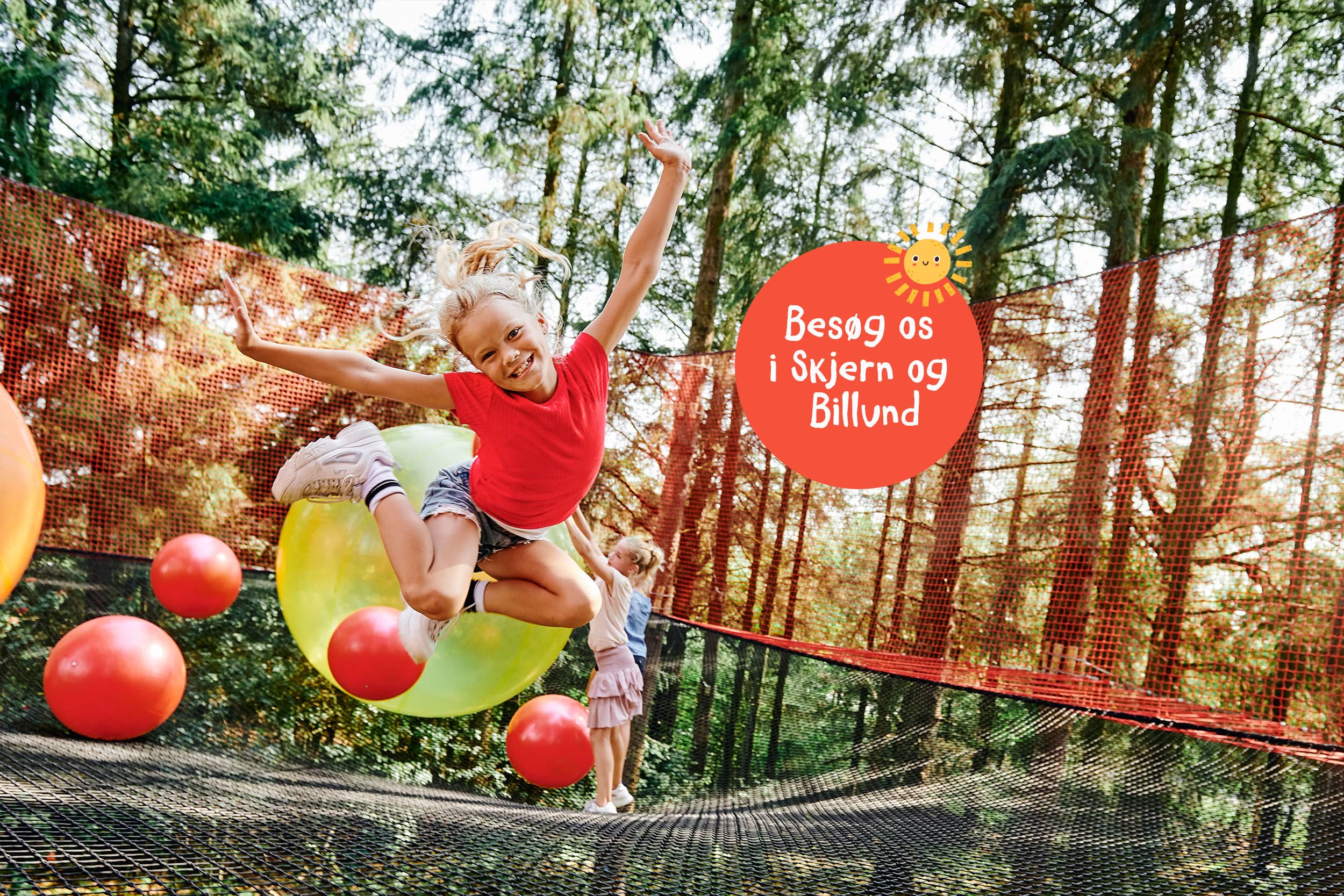 Stort net i træerne, røde og gule bolde og børn der leger.