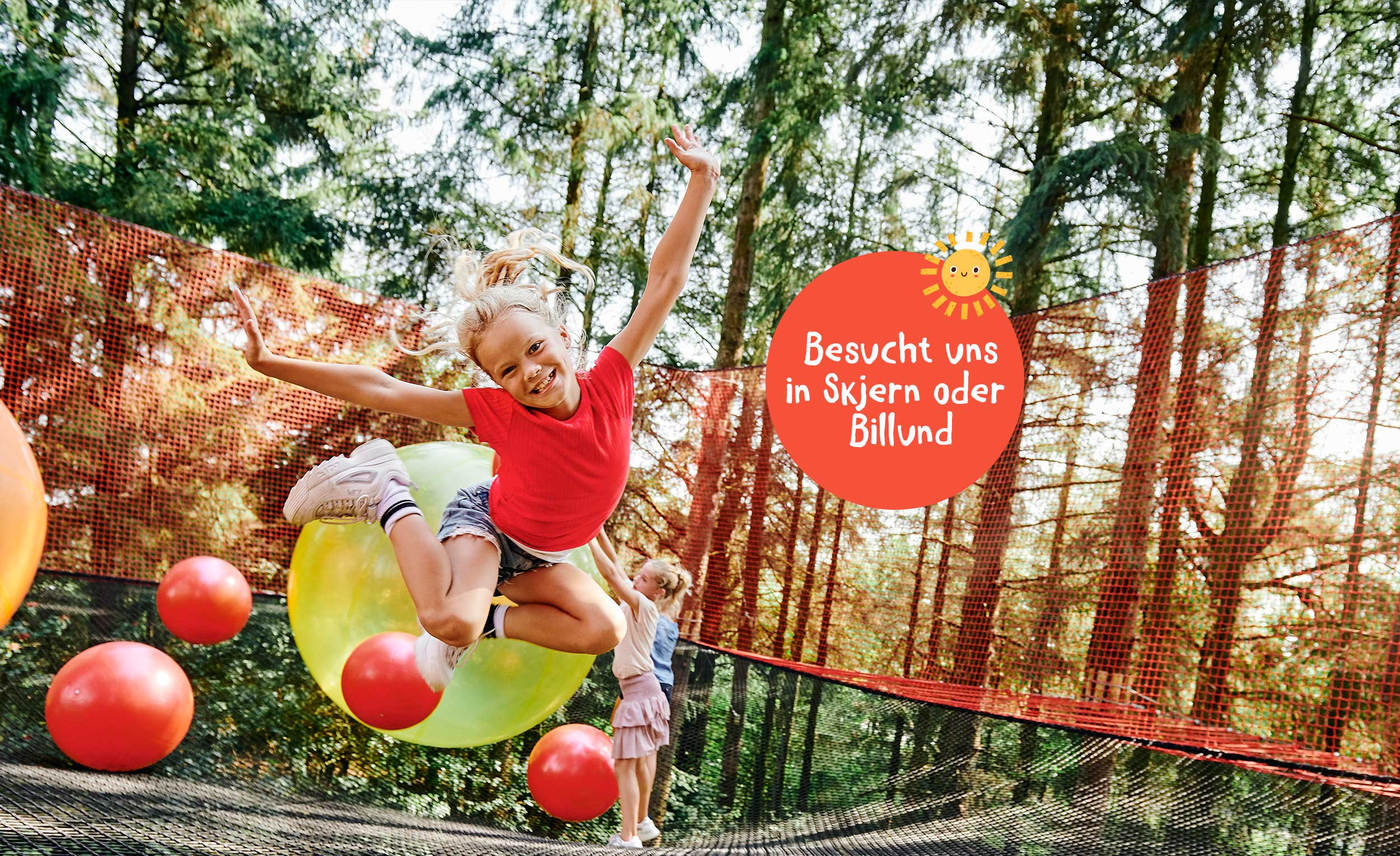 Ein fröhliches Mädchen springt in einem großen Netz im WOW PARK. Im Hintergrund sind andere Kinder zu sehen. Außerdem sieht man bunte Bälle.