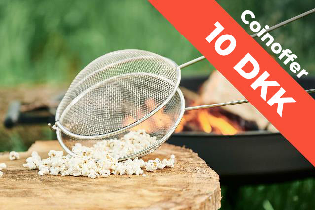 A popcorn net and popcorn by a campfire.
