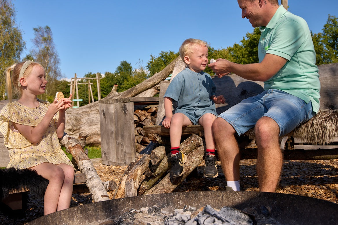 A father and two children making s’mores by a bonfire at WOW PARK.