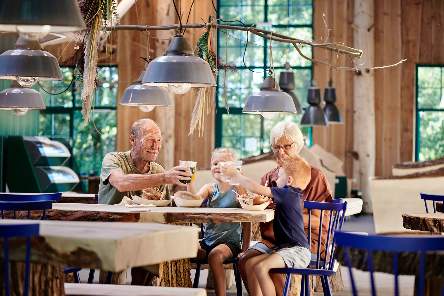 Grandparents and grandchildren are sitting in Madladen at WOW PARK Billund, enjoying food and drinks