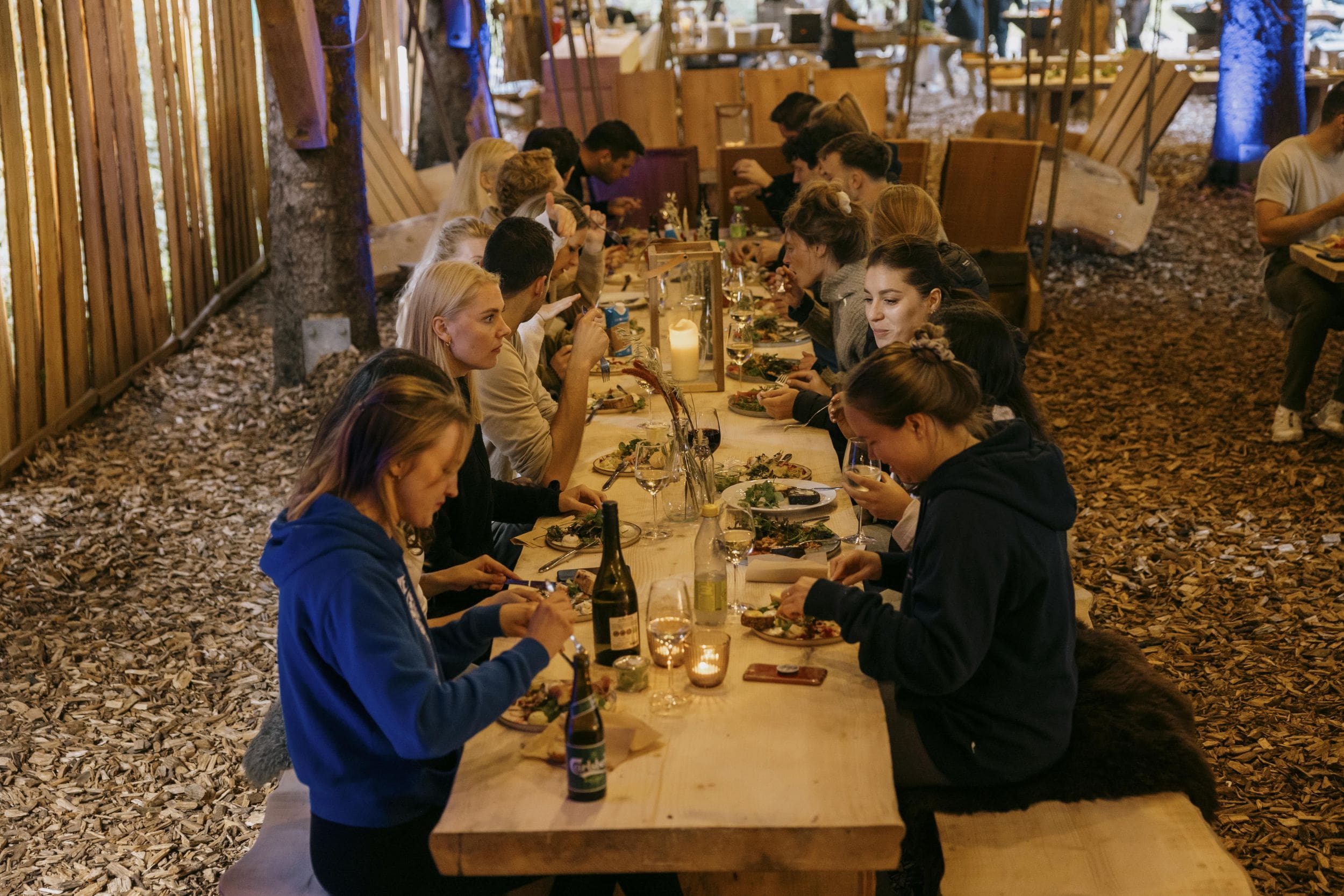 En gruppe kollegaer til teamevent i WOW PARK Billund hygger sig i Skovhuset og spiser lækker mad.