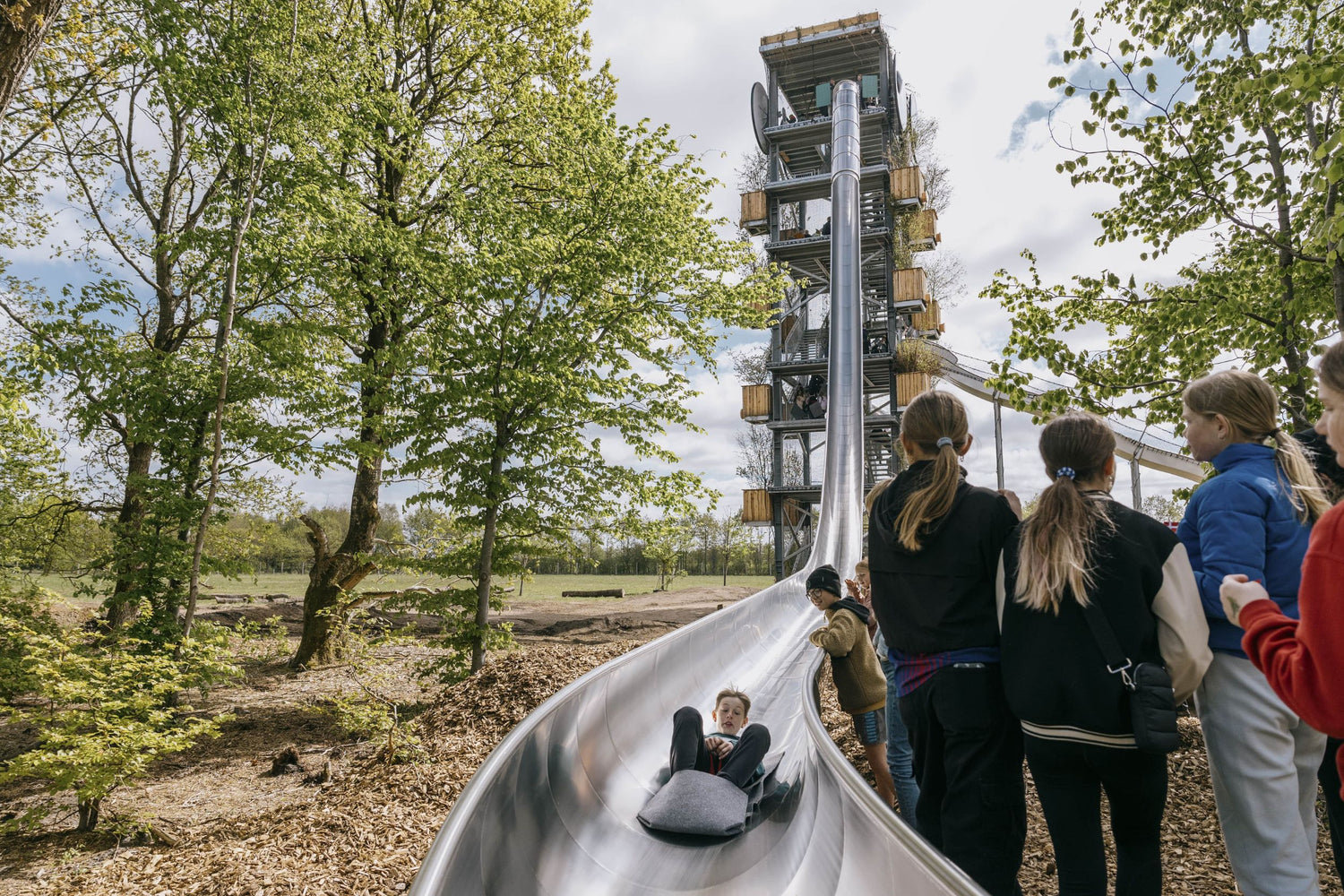 En dreng er på vej ned ad GIGANTEN i WOW PARK Billund, mens andre børn kigger på