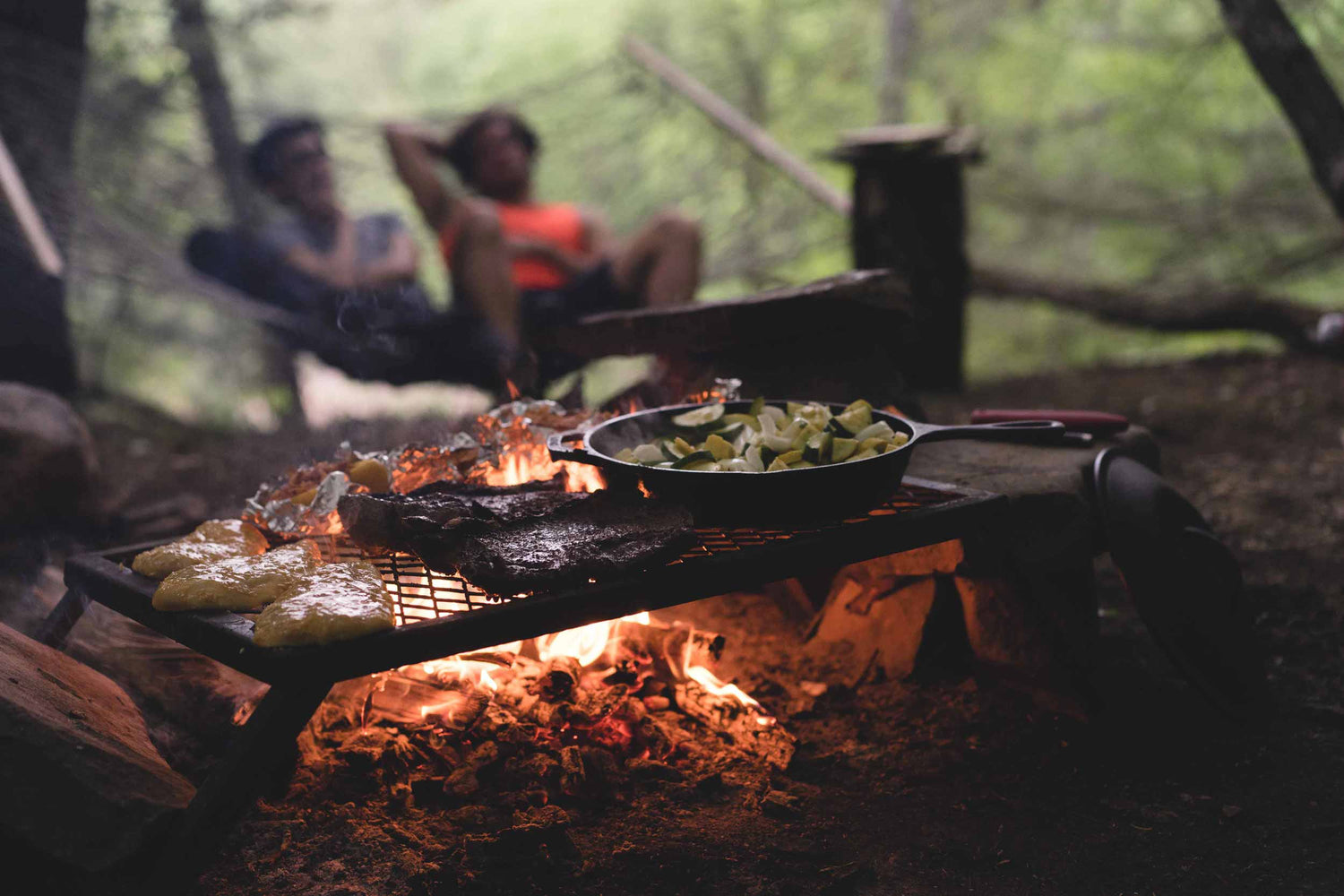 Some people sitting by a campfire making twist bread.