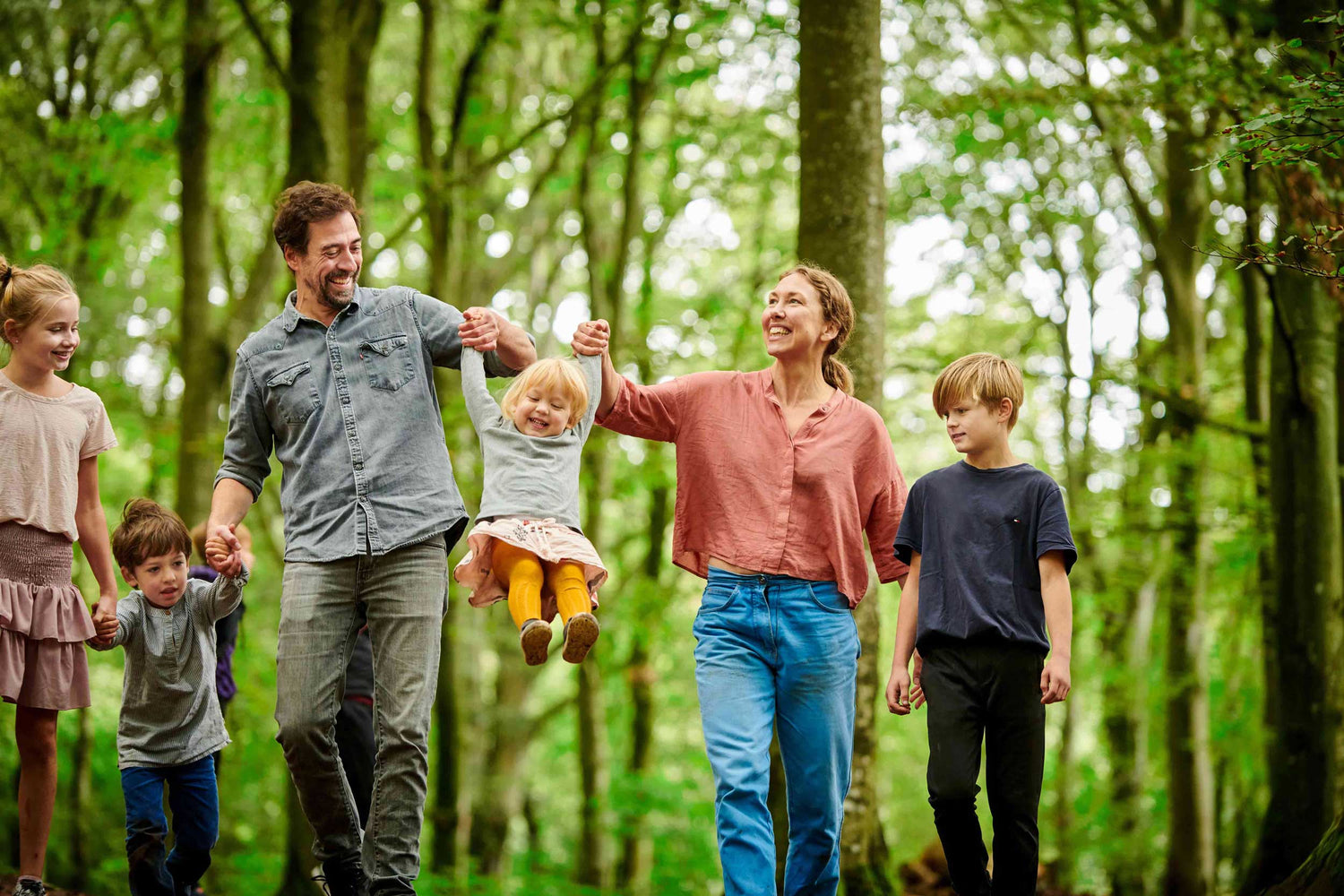 En hel familie går i skoven i WOW PARK - de ser glade ud.