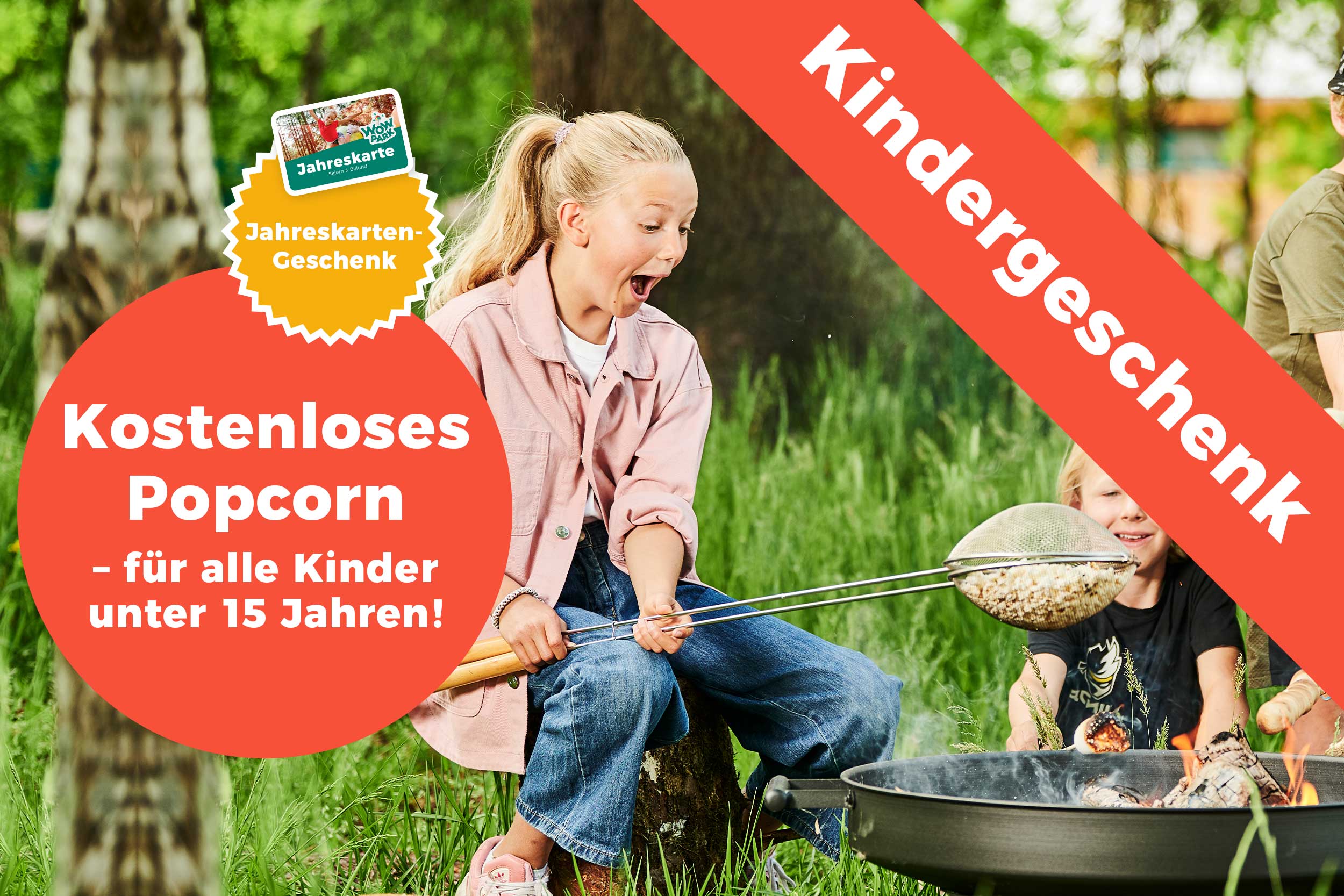 Man sieht einige Kinder, die am Lagerfeuer im WOW PARK sitzen und Popcorn zubereiten.