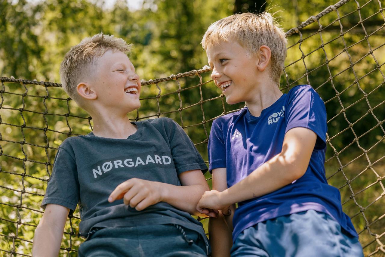 To drenge, der griner, ligger i en hængekøje