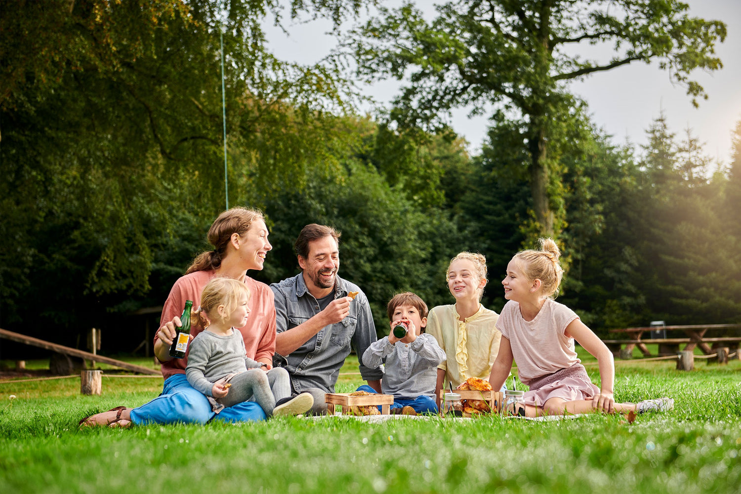 En familie på 5 personer sidder på græsset i WOW PARK.