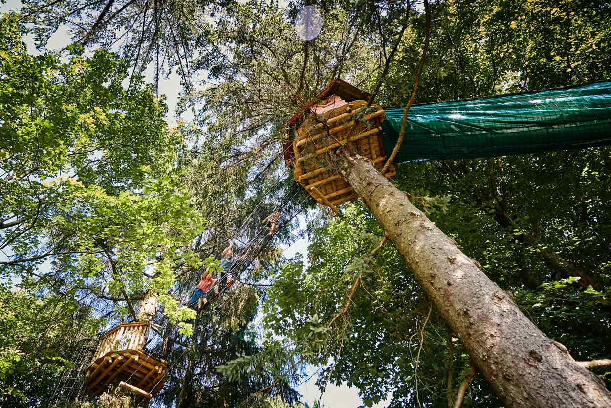 A treehouse and nets seen from below. People are walking in the net.