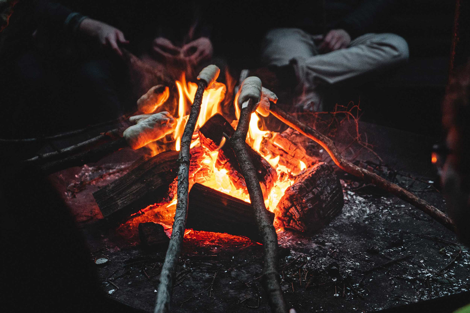 Bål med flammer og to personer ved bålet