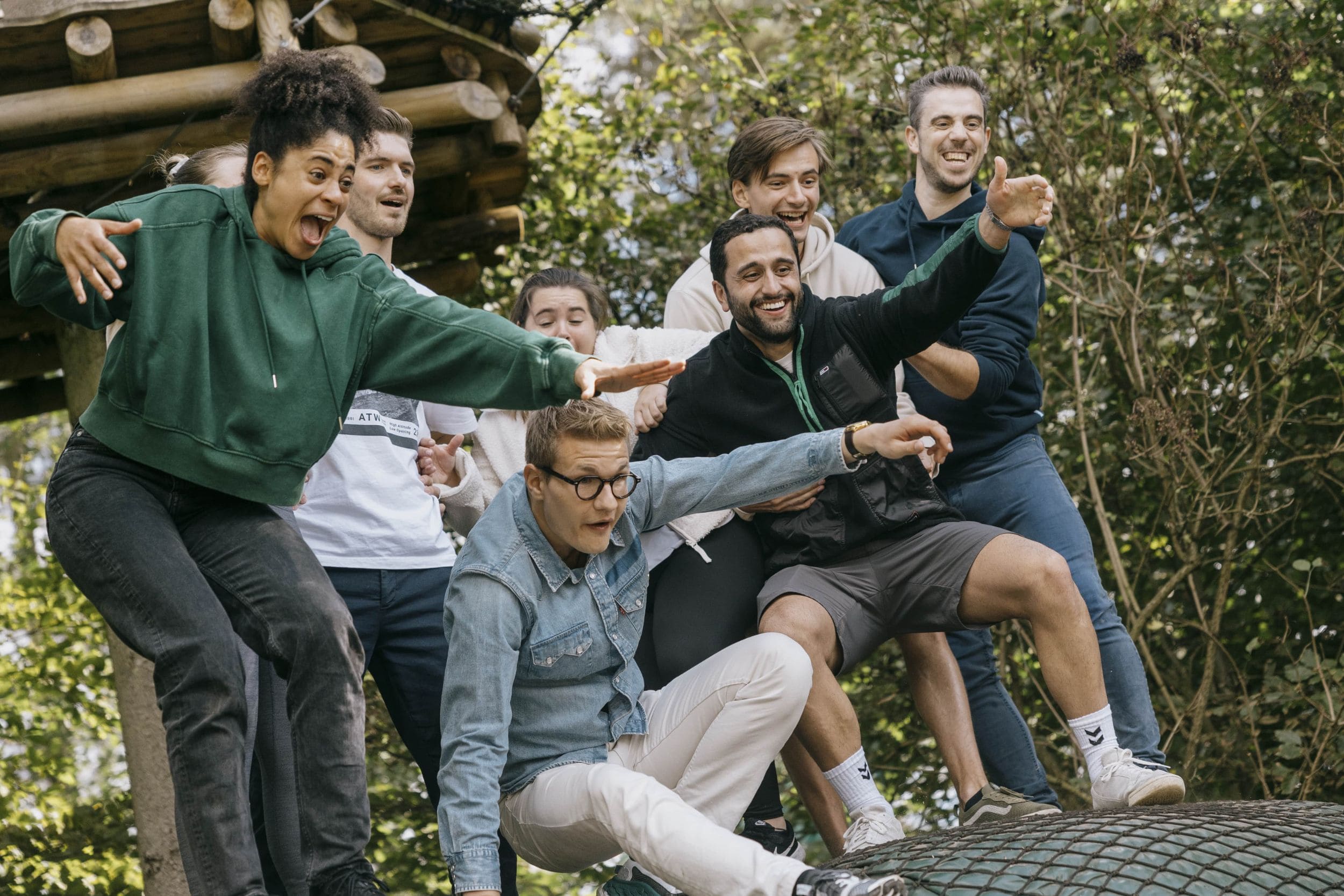 A happy group of young people at a team event in WOW PARK. They are engaged in teambuilding activities in the forest.