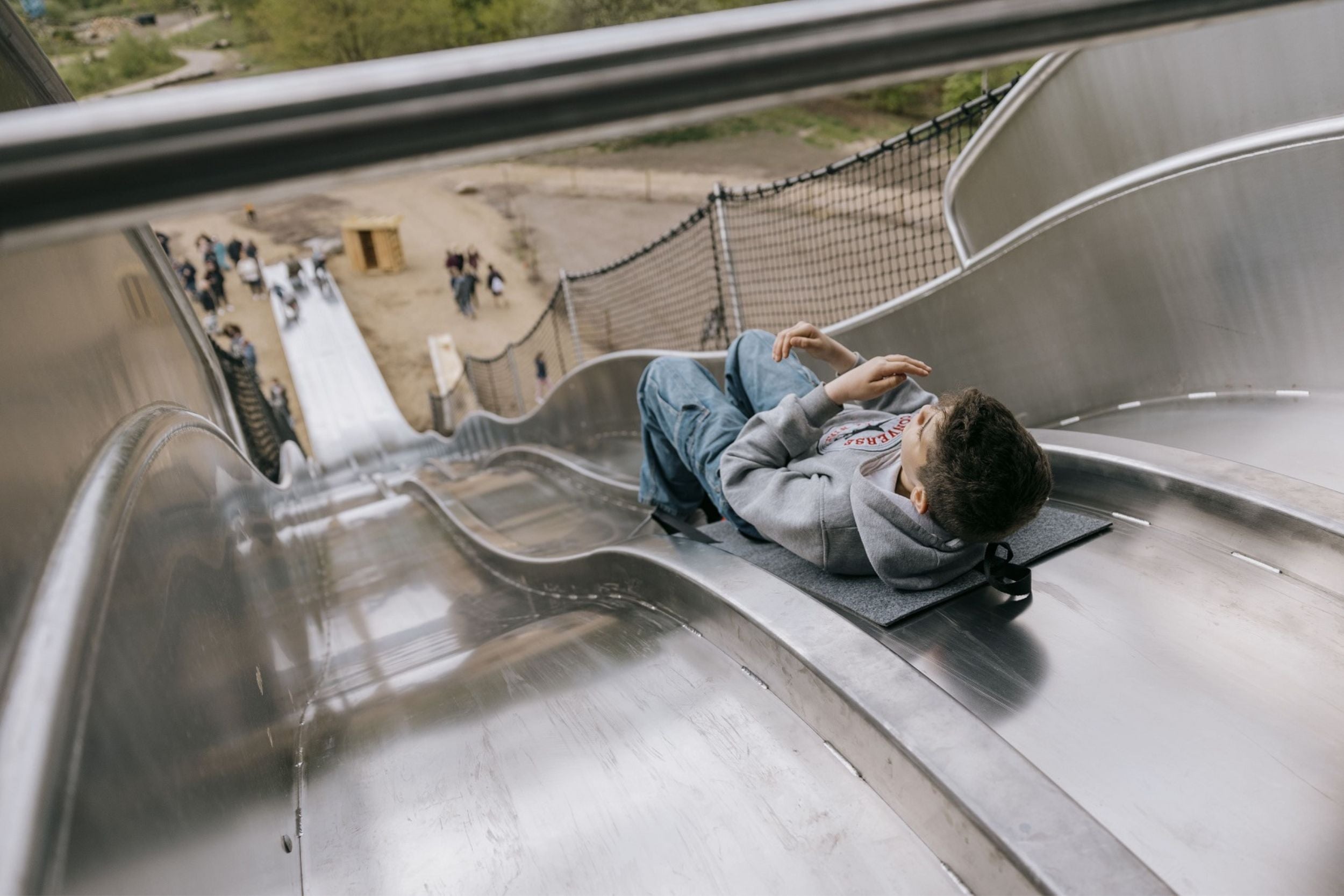 A boy is lying down and on his way down the SKOVRACEREN, a roller coaster at WOW PARK Billund where three people can sit side by side. He is lying on a mat.