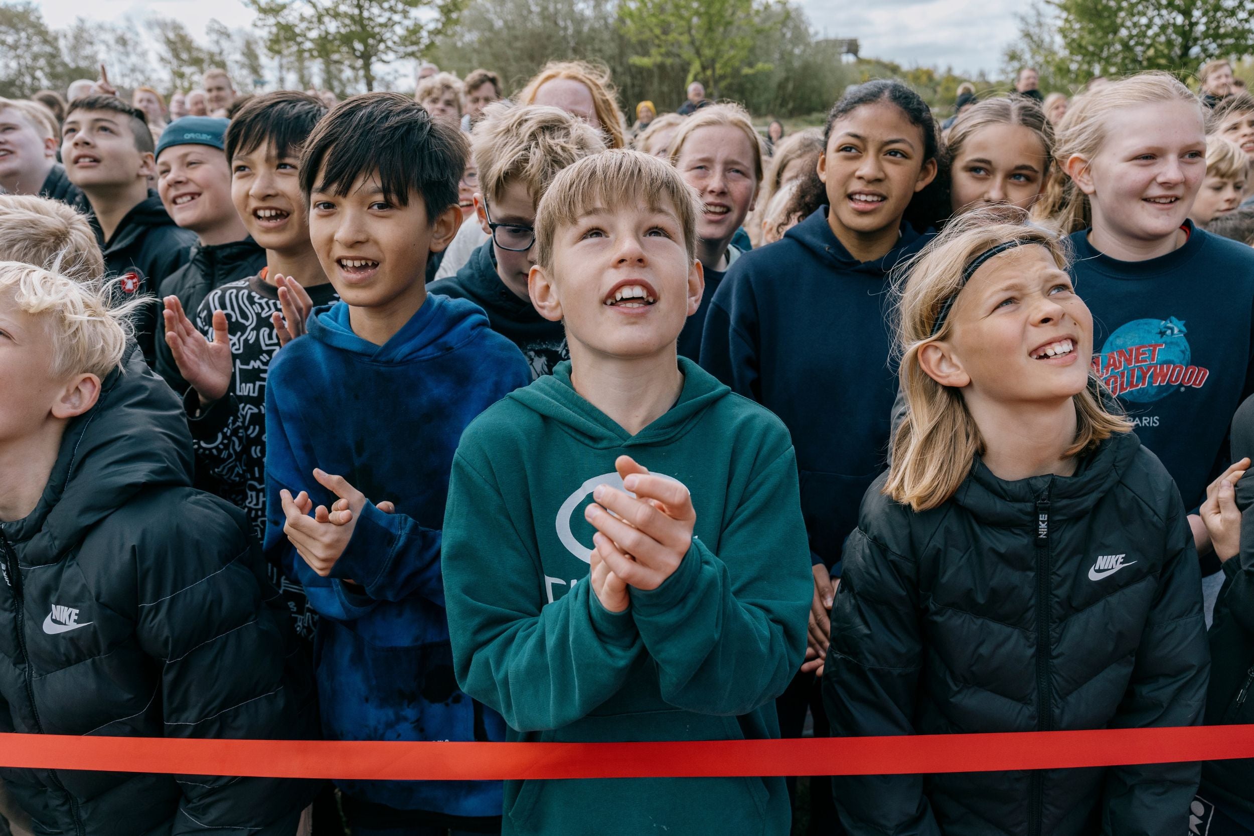 A large group of children are standing together, watching the same activity at WOW PARK.