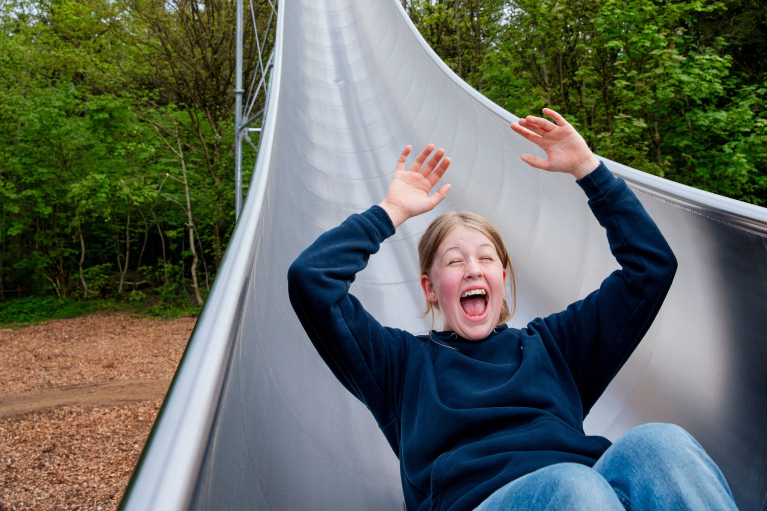 Ein Mädchen, das offensichtlich Spaß hat, fährt die SPINNE im WOW PARK Skjern hinunter.